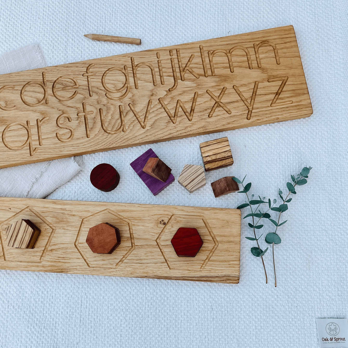 Oak & Sprout alphabet tracing and shape puzzle boards flatlay with Padauk, Purpleheart, Zebrano and Walnut pieces on linen