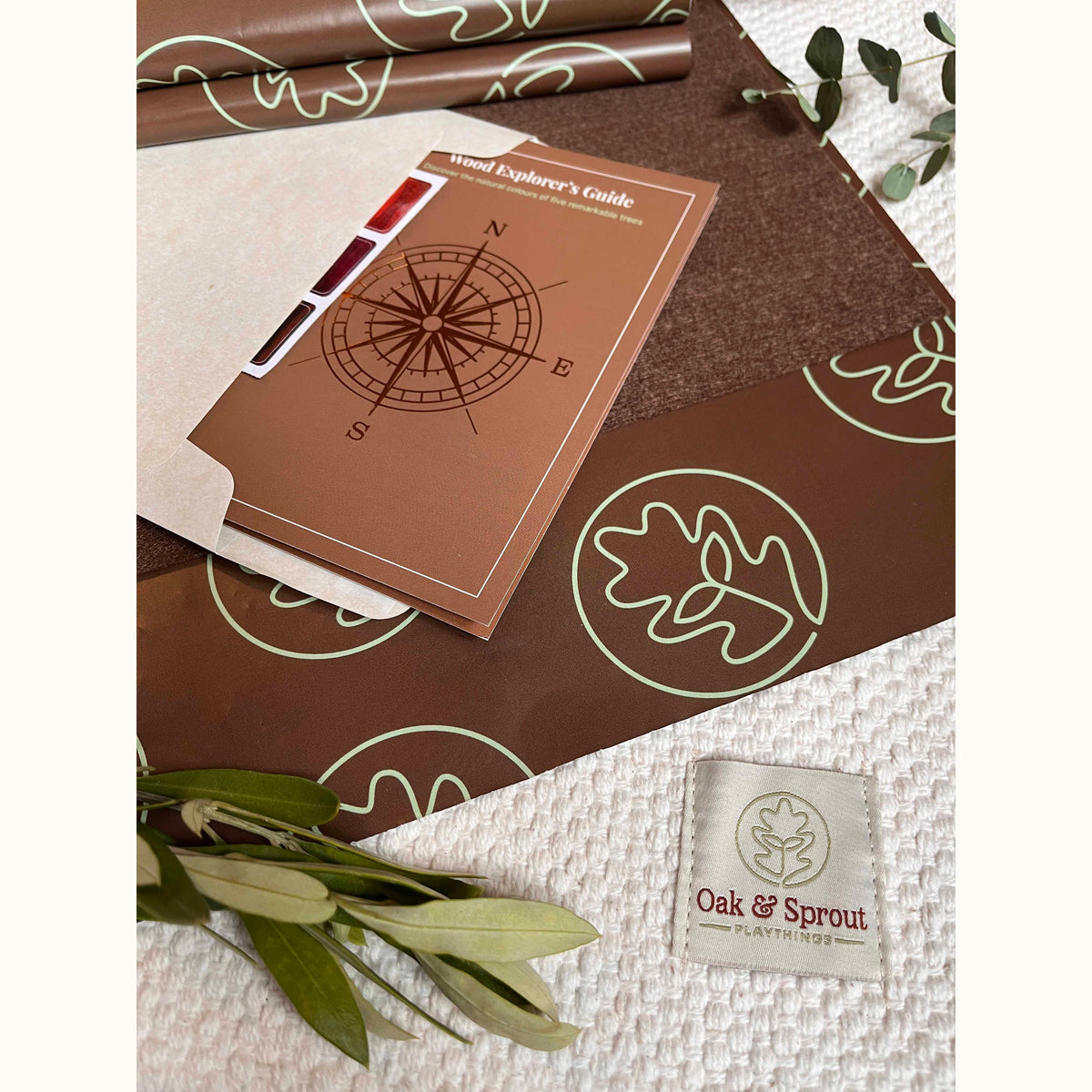 Geo Nest puzzle gift packaging with Wood Explorer's Guide booklet, oak leaf wrap, and Oak & Sprout fabric label