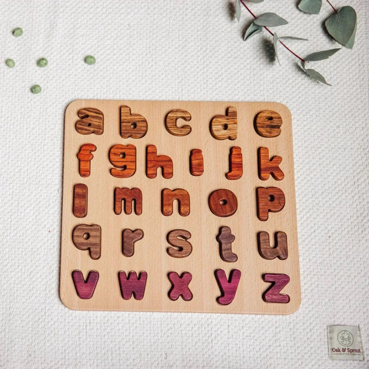 Lowercase Alphabet Puzzle fully assembled, 26 tigerwood, mahogany, walnut and purpleheart letter pieces in pale board
