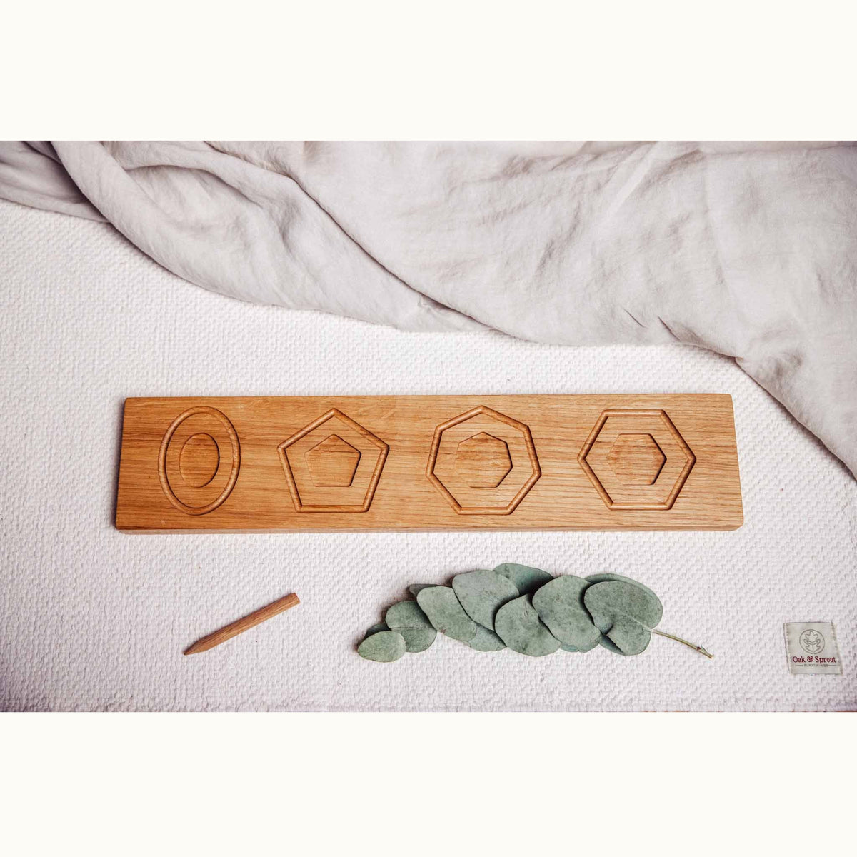 Trace & Place oak board showing engraved oval, pentagon, heptagon and hexagon tracing guides, styled on white playmat