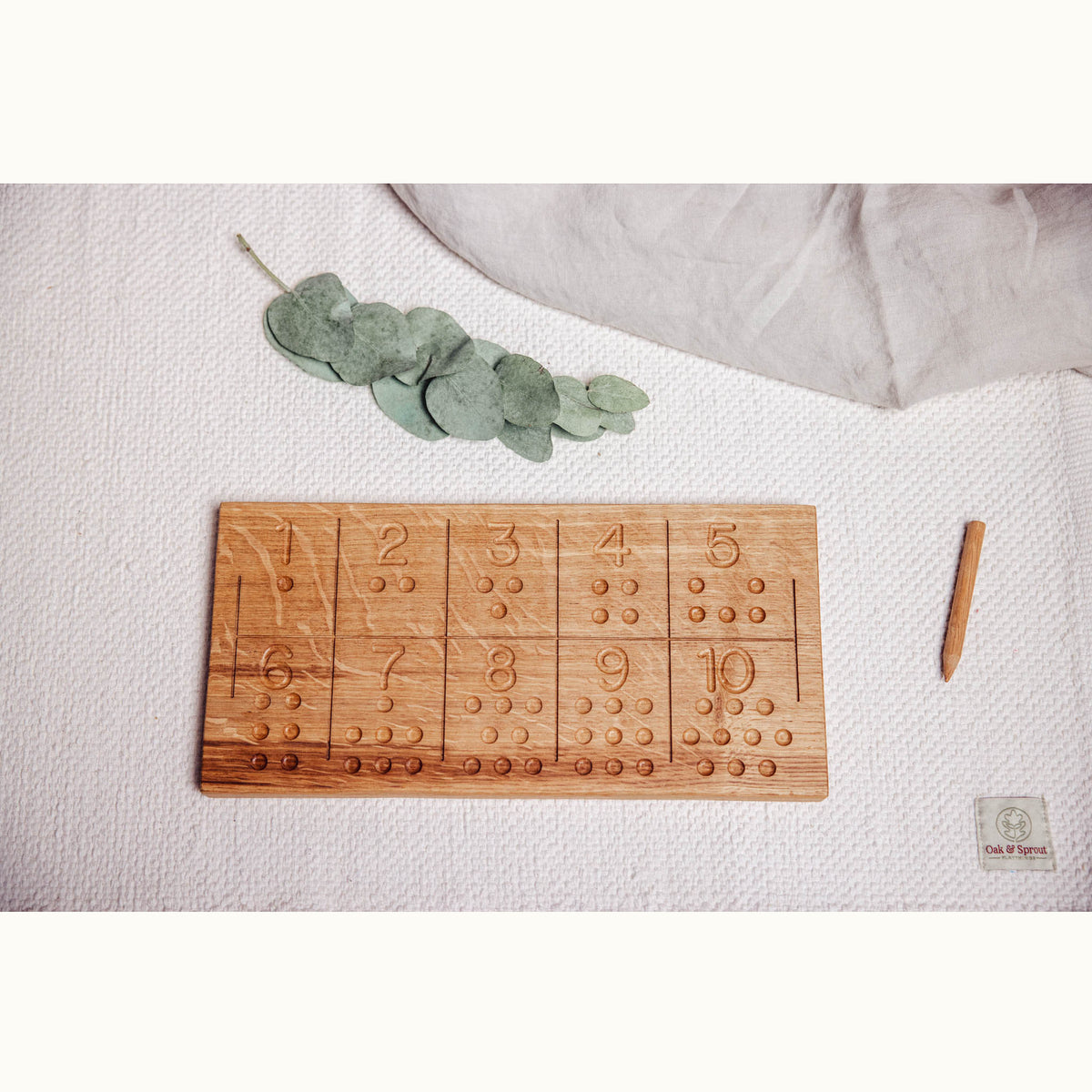 Numbers Tracing & Balls oak board flat lay showing numbers 1–10 with raised counting dots and wooden stylus on linen