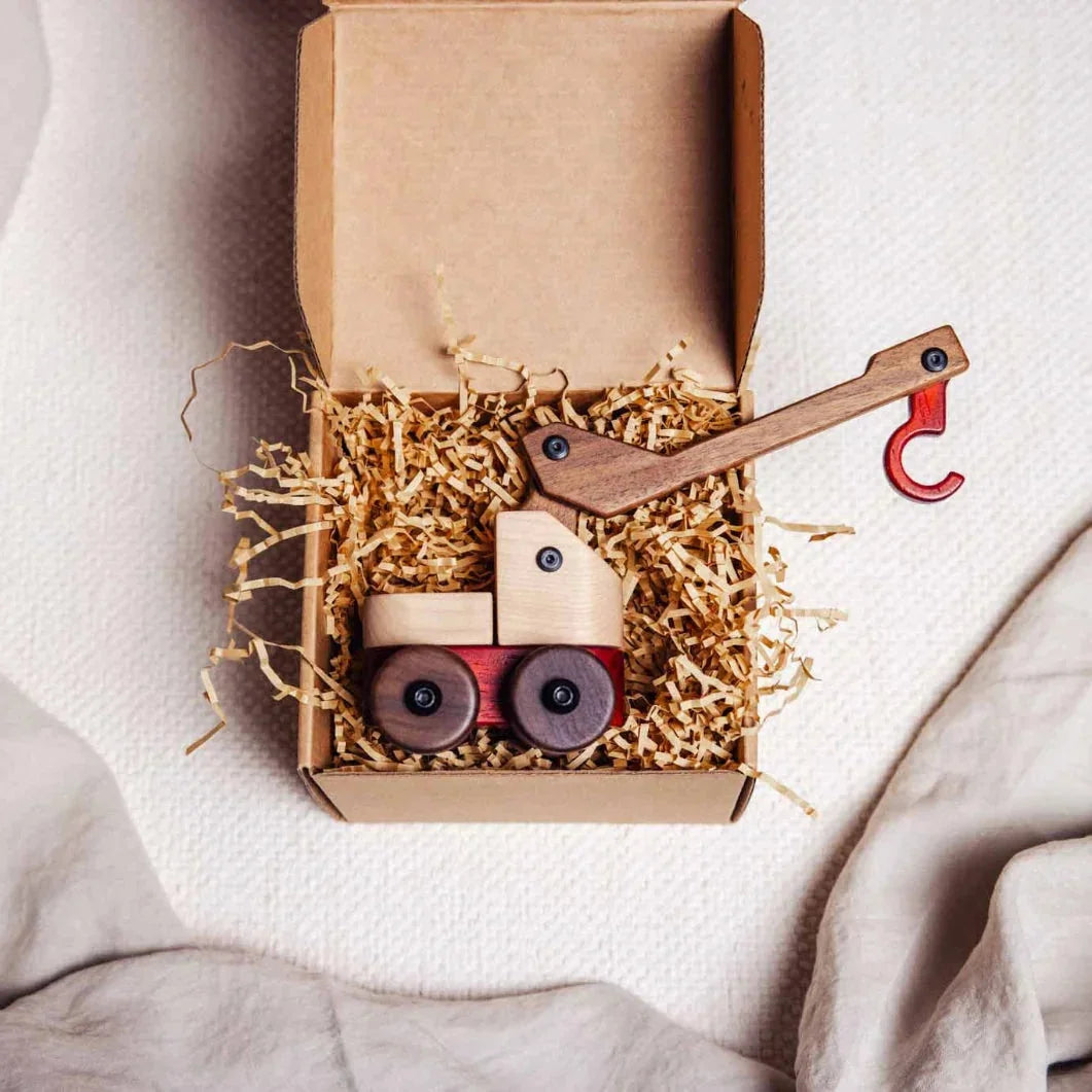 Complete Wooden Vehicles Set gift packaging: kraft box with crane toy in maple, walnut, and padauk nestled in shredded paper