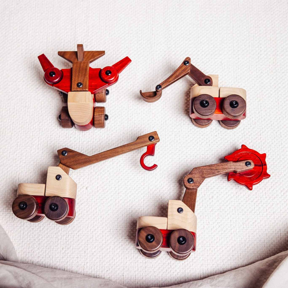 Walnut & Maple Crane shown in a flat-lay range shot with three other maple, walnut, and padauk construction vehicles on linen