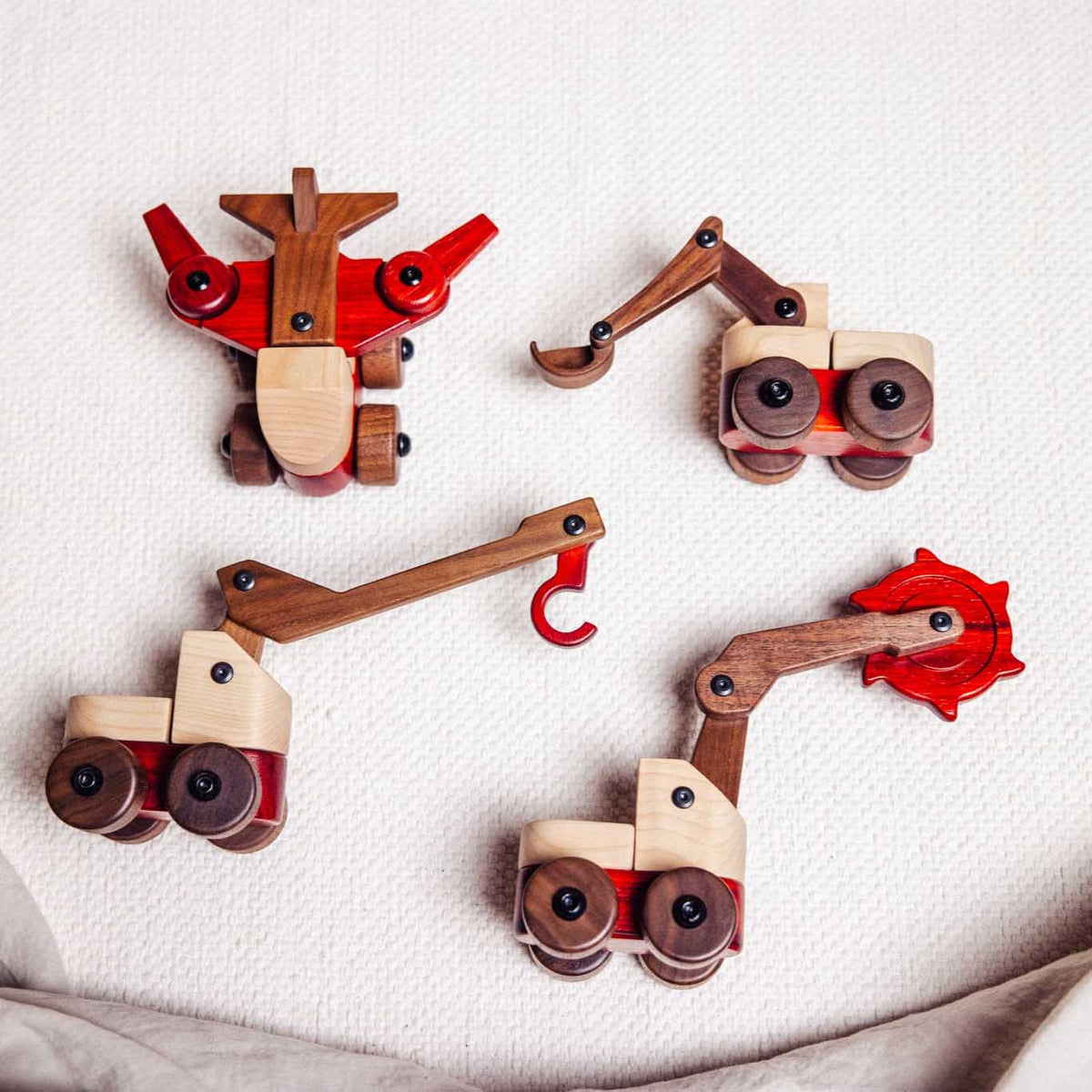 Complete Wooden Vehicles Set flat-lay — aeroplane, excavator, crane and saw machine in maple, walnut and padauk on linen