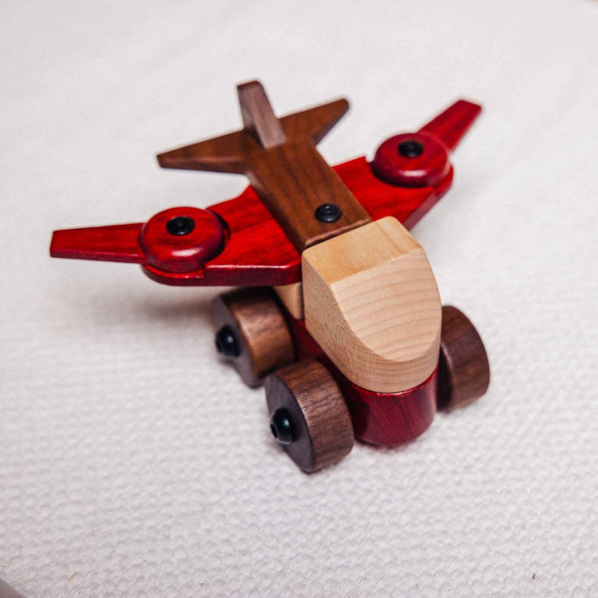 Walnut & Padauk Aeroplane front angle: coral-red padauk wings, dark walnut tail and wheels, pale maple nose block