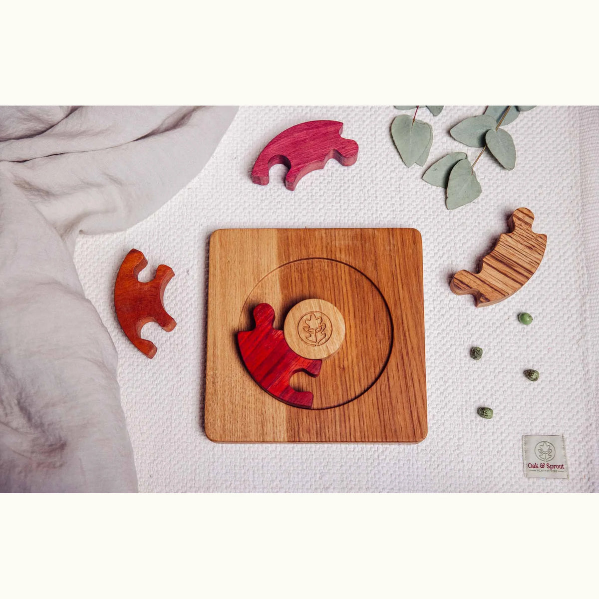 Unity Puzzle partially disassembled on playmat, oak base with padauk, purpleheart, tigerwood and zebrano segments scattered
