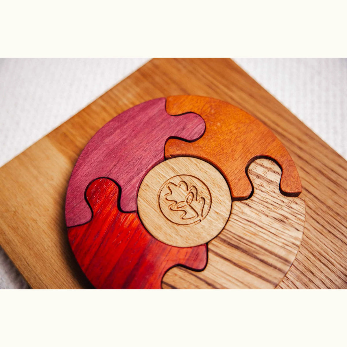 Unity Puzzle partially assembled showing Purpleheart, Padauk and Tigerwood curved segments around engraved central disc on oa