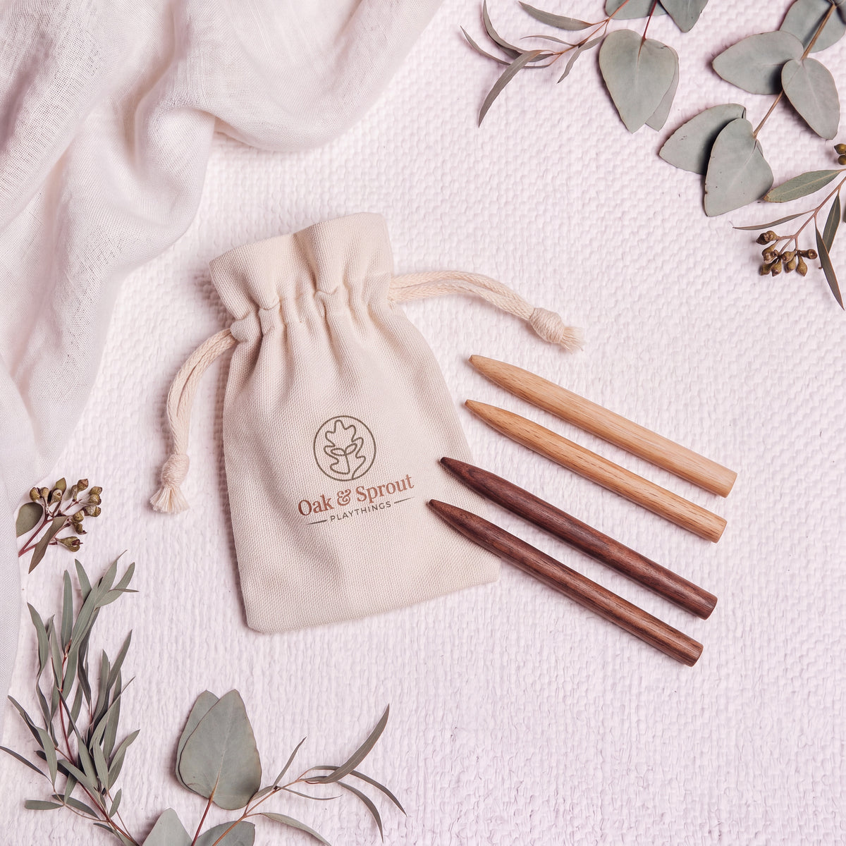 Two oak and two walnut tracing styluses beside an Oak & Sprout cotton drawstring pouch