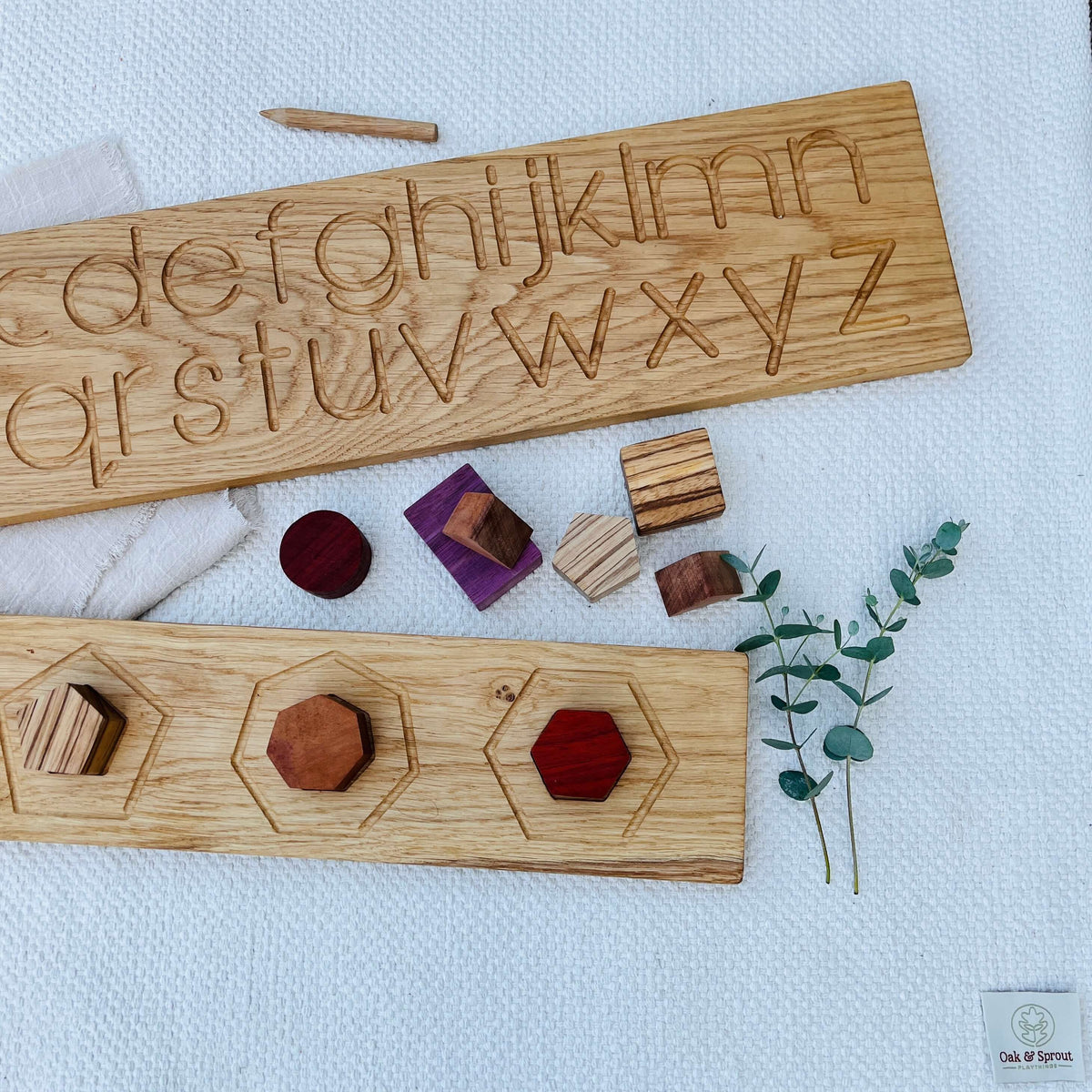 Oak & Sprout gift card flat-lay with alphabet board, puzzle pieces in Padauk, Purpleheart, Zebrano and Walnut on linen