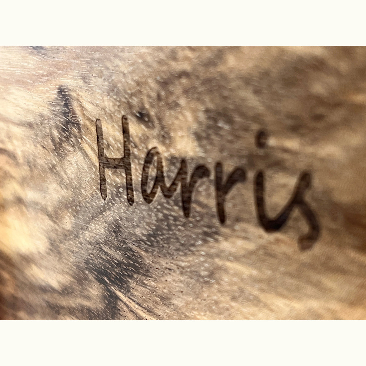 Close-up of laser-engraved name 'Harris' in cursive script on African Satinwood — Shape Sorting House personalisation detail