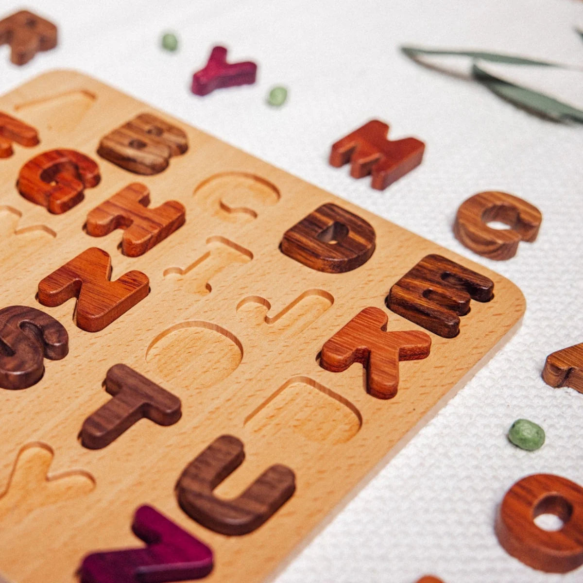 Oak & Sprout uppercase alphabet puzzle board partially assembled, walnut, tigerwood, purpleheart and mahogany letter pieces s