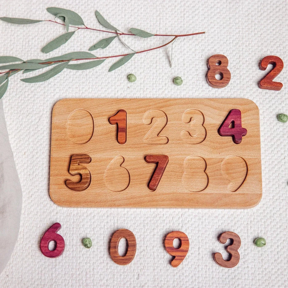 Oak & Sprout Wooden Number Puzzle partially assembled, with Purpleheart, Walnut and Tigerwood digit pieces scattered beside t