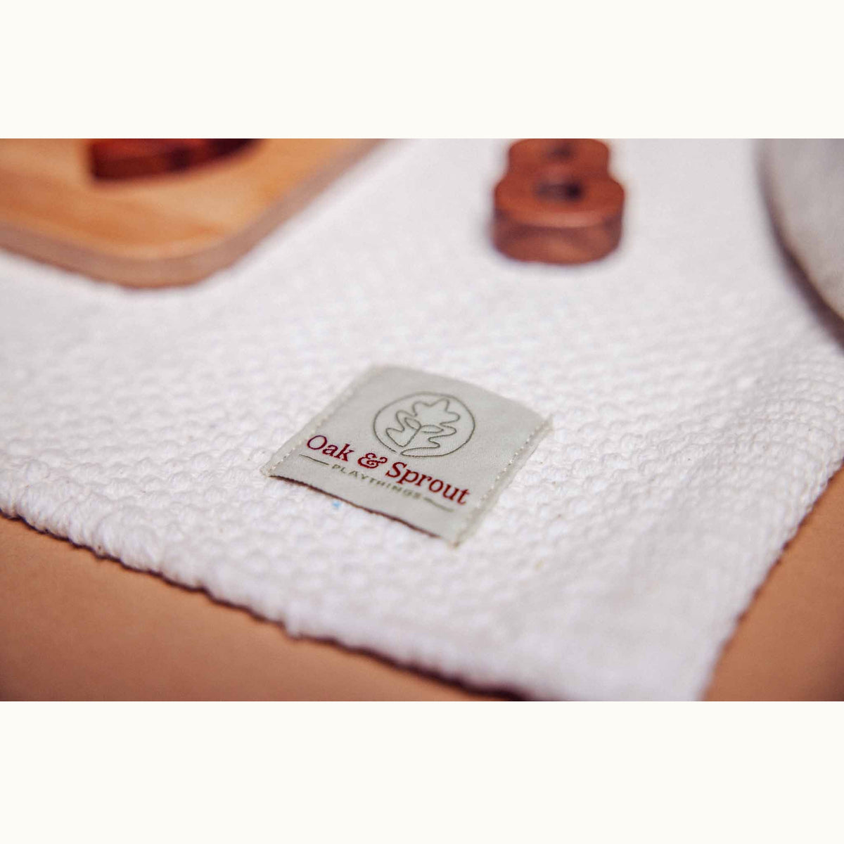 Oak & Sprout woven label on the Literacy & Numeracy Bundle playmat, with beech board and a walnut numeral behind