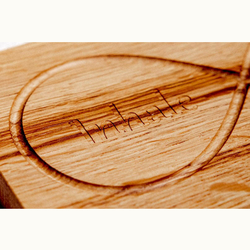 Infinity Breathing Board oak surface close-up showing laser-engraved inhale text and finger-trace infinity loop groove