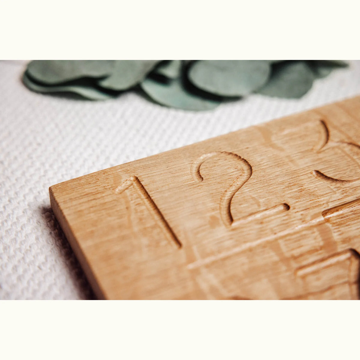 Numbers Tracing & Balls oak board close-up showing hand-carved numerals 1 and 2 with natural honey grain detail