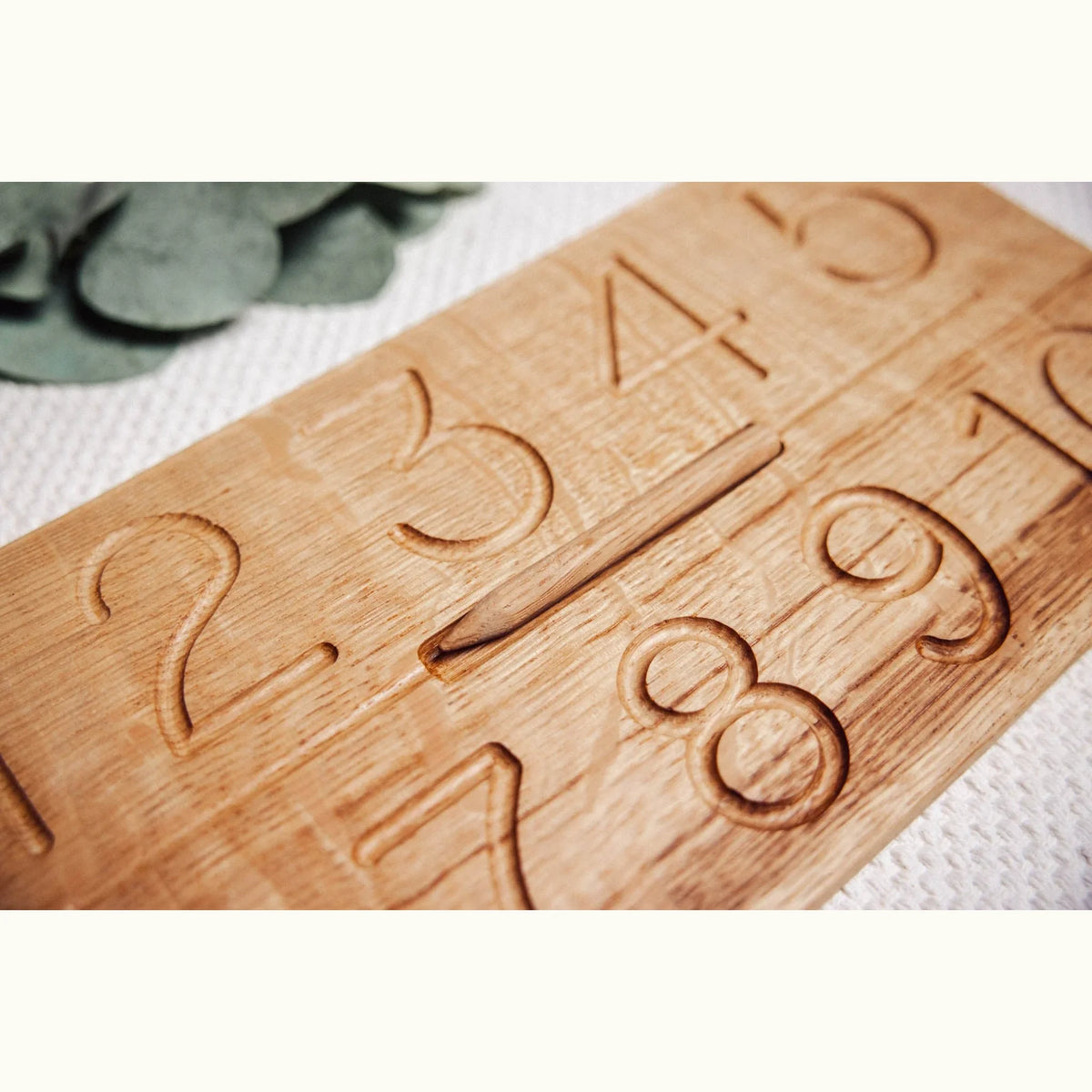 Close-up of Numbers Tracing & Balls oak board showing CNC-carved number grooves with warm honey grain detail