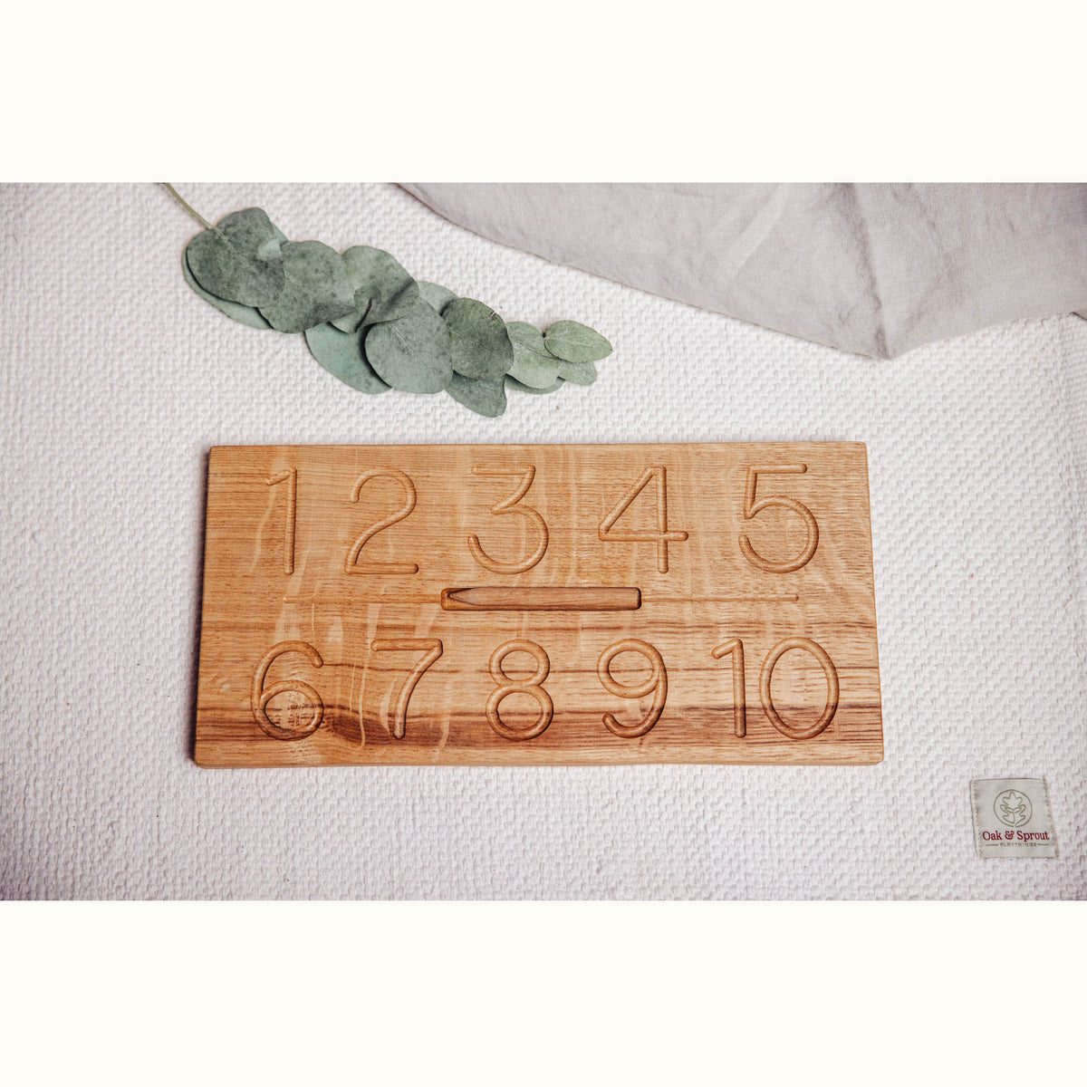 Numbers Tracing & Balls oak board flat-lay showing engraved numerals 1–10 in two rows with stylus in central slot