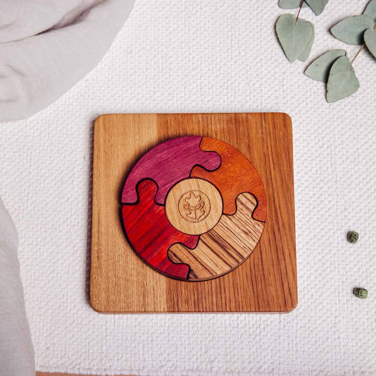 Unity Puzzle assembled on linen playmat showing Purpleheart, Padauk, Tigerwood and Zebrano curved segments in oak base