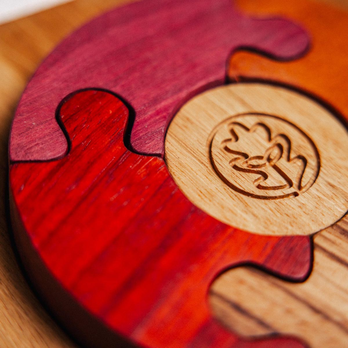 Wooden puzzle piece with a logo on a wooden surface