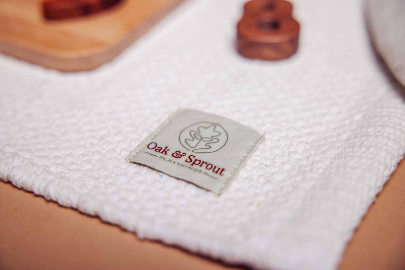 Oak & Sprout branded label on white textured play mat, Trace & Place board with dark Tigerwood or Padauk pieces softly